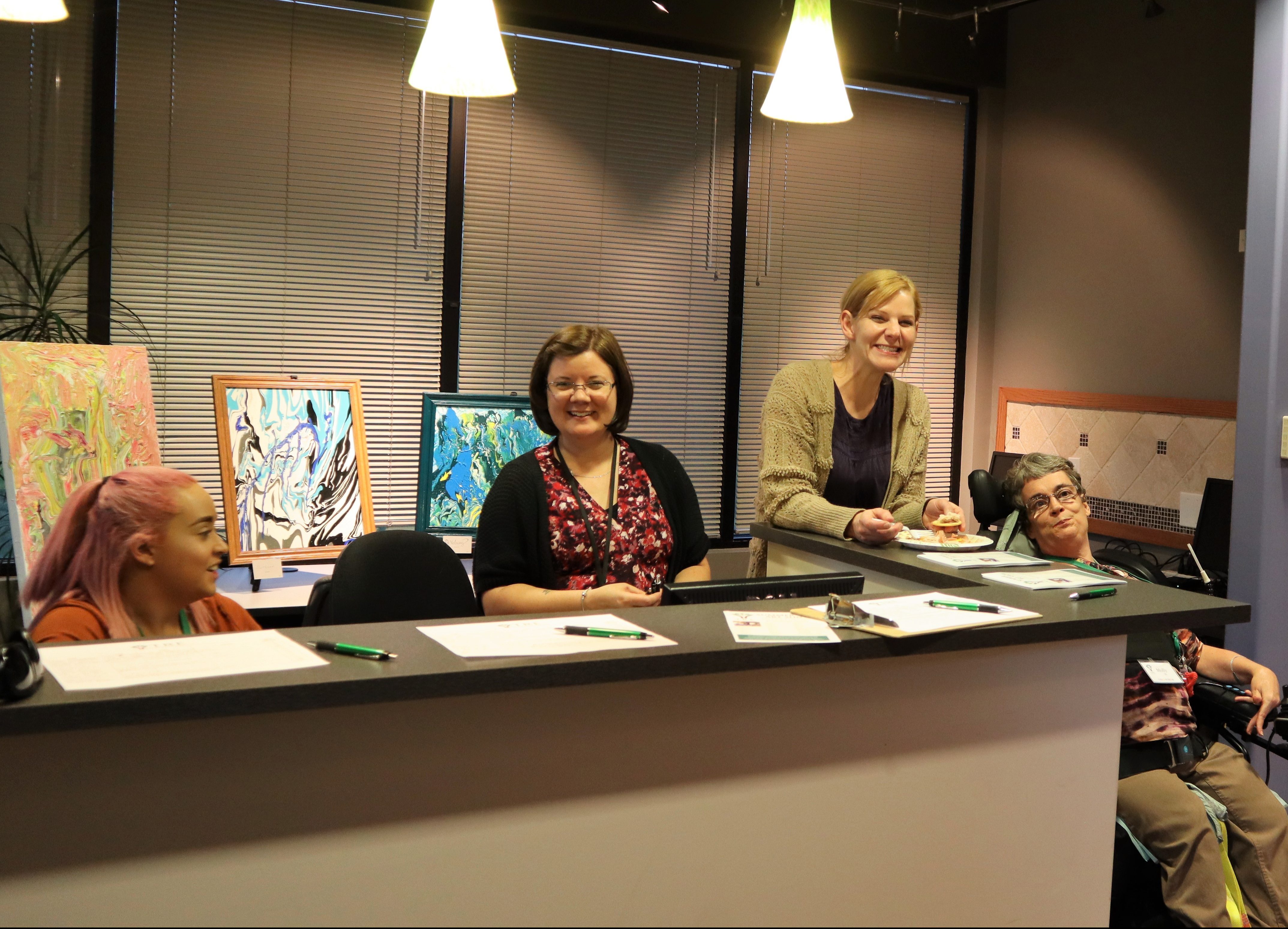 people smiling at a desk to greet guests of the Art Show