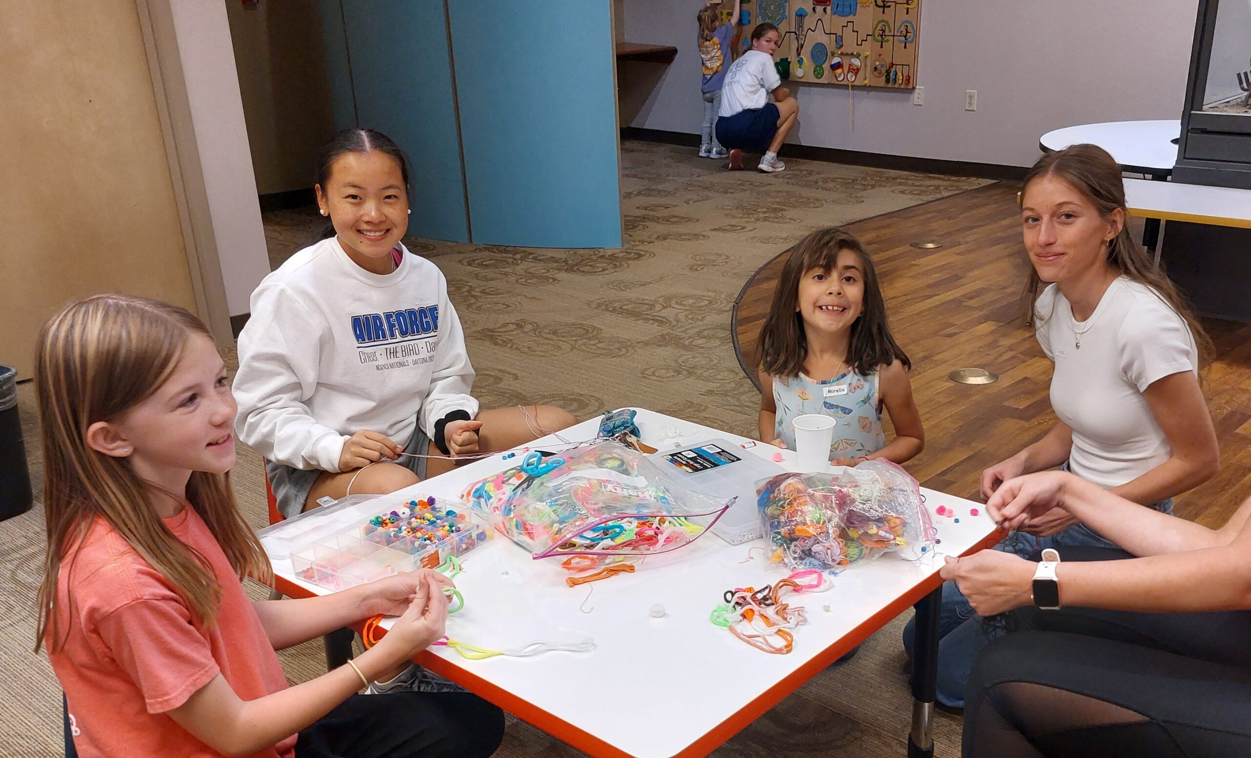 young adults and children color at a table