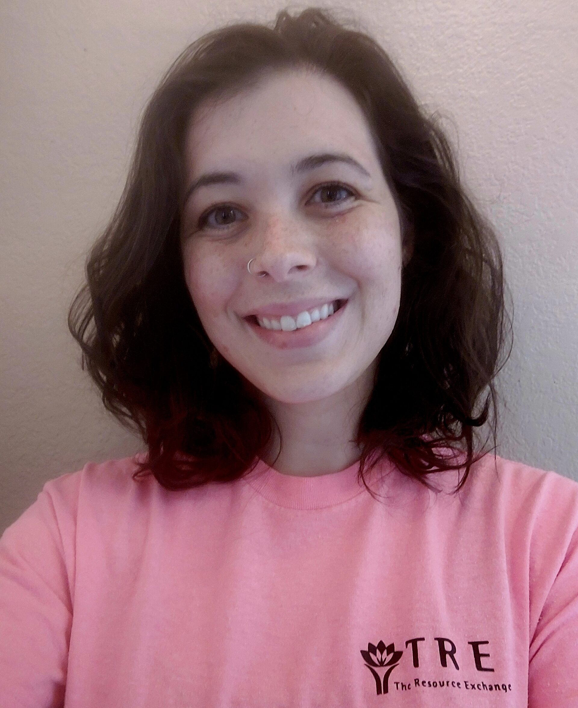 woman with brown hair wearing pink shirt smiles at viewer