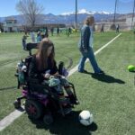 Young girl in motorized wheelchair playing with soccer ball